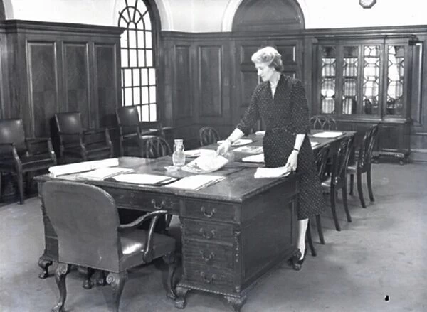 ecretary prepares a boardroom for a meeting, 1950 s