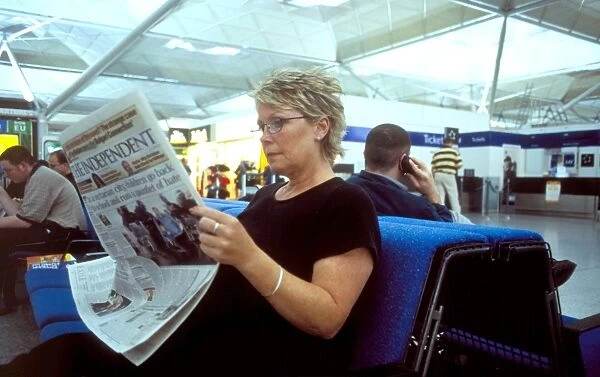 Passenger reading. woman reading newspaper at stanstead airport waiting louge Brotchie