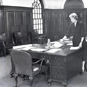 ecretary prepares a boardroom for a meeting, 1950 s